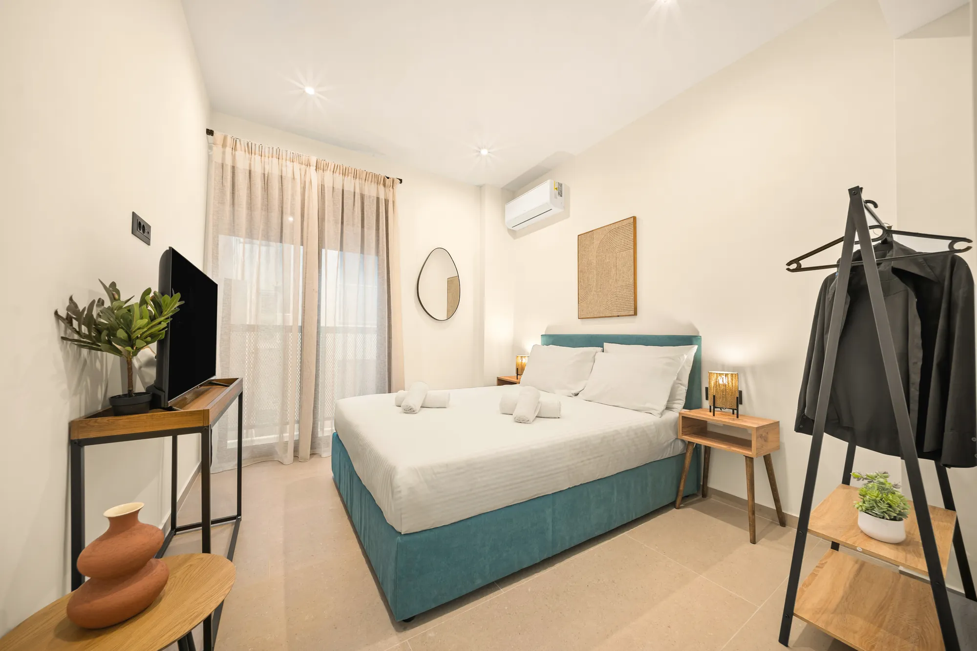 ORMOS Piraeus, a room with the teal bed, the olive tree and the clothes rail
