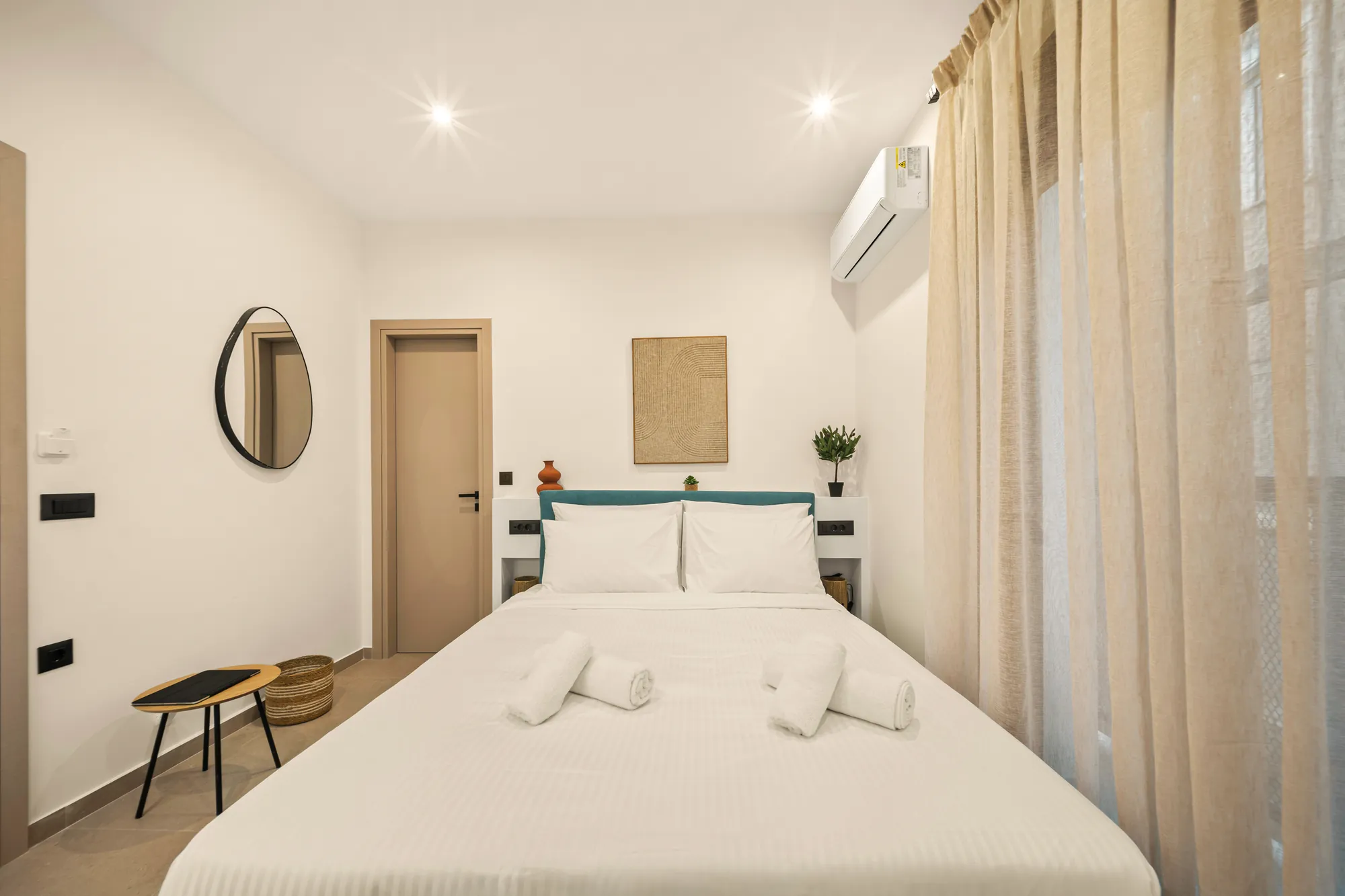 ORMOS Piraeus, the bed under the woven artwork, the door to the bathroom beside it