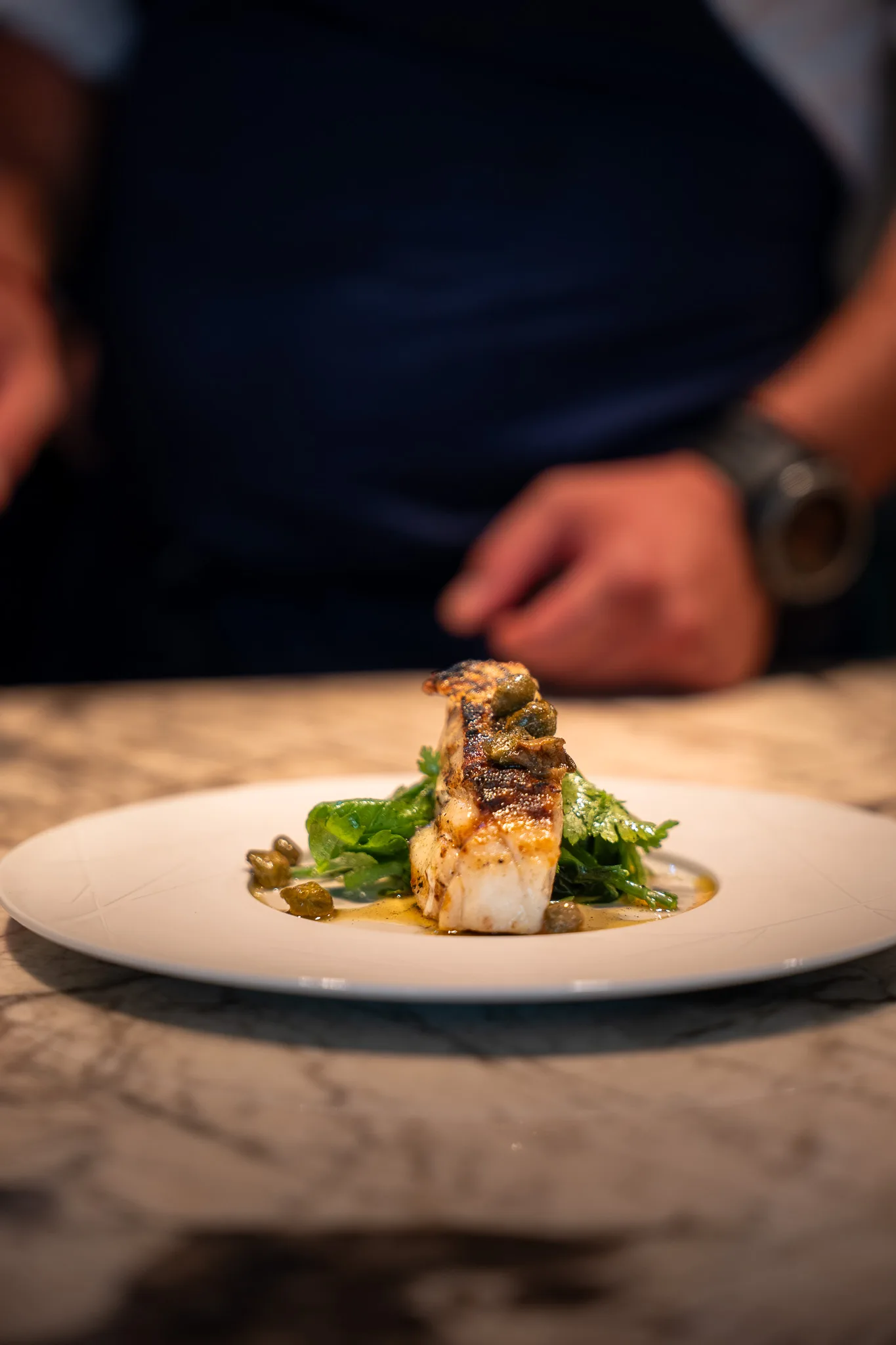 A plated fish course on a white plate