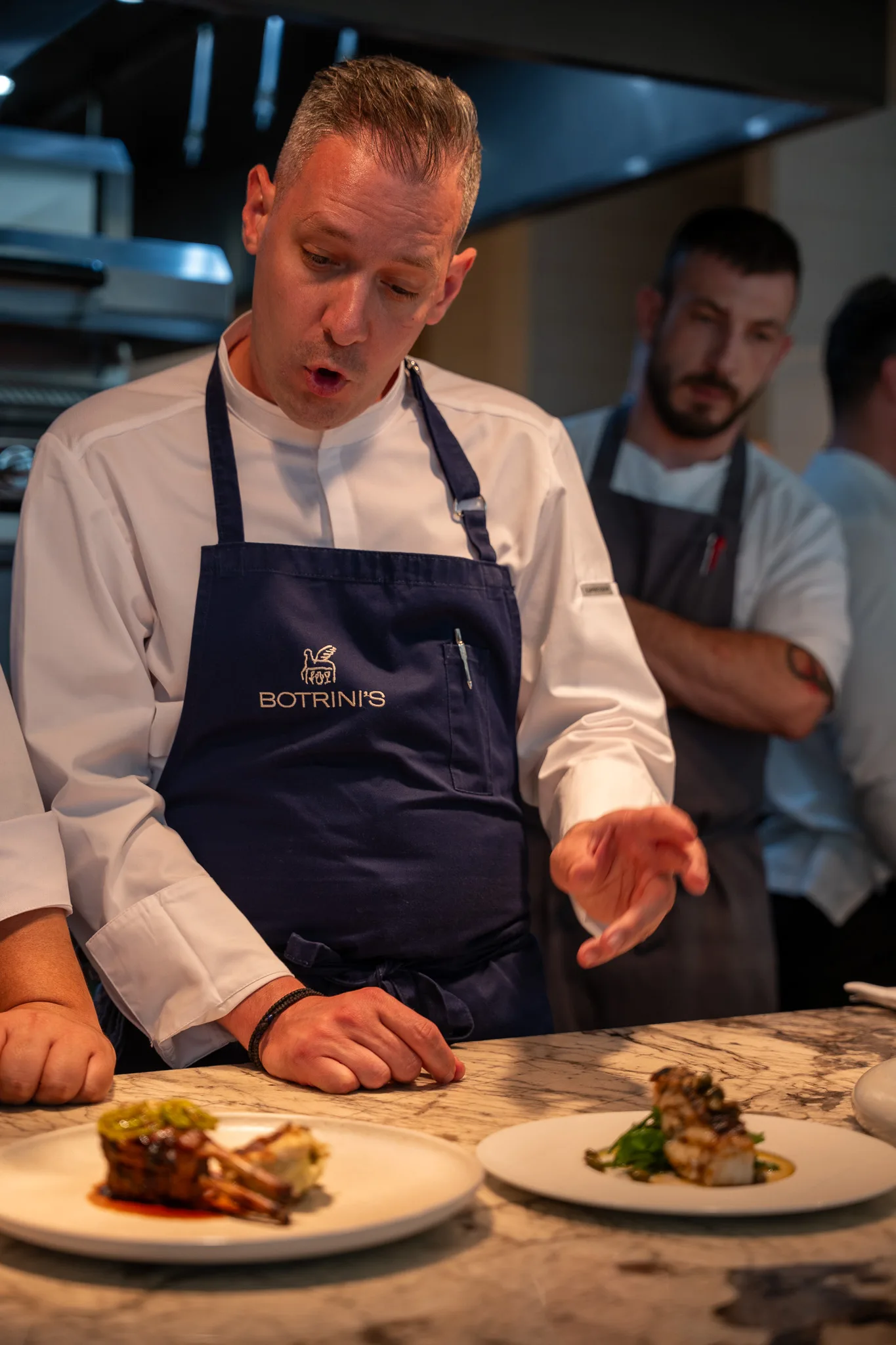 A cook in a Botrinis apron finishing a plate