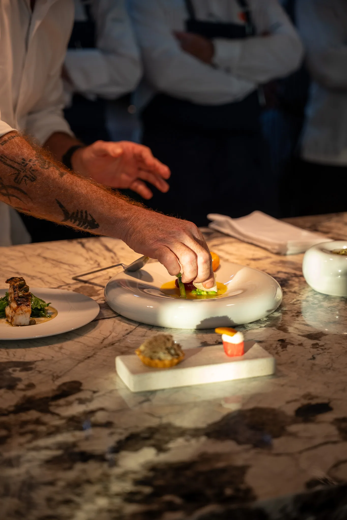 Hands finishing a plate on the lit pass